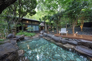 A traditional Japanese-style building with a koi pond, wooden deck, and surrounding greenery.