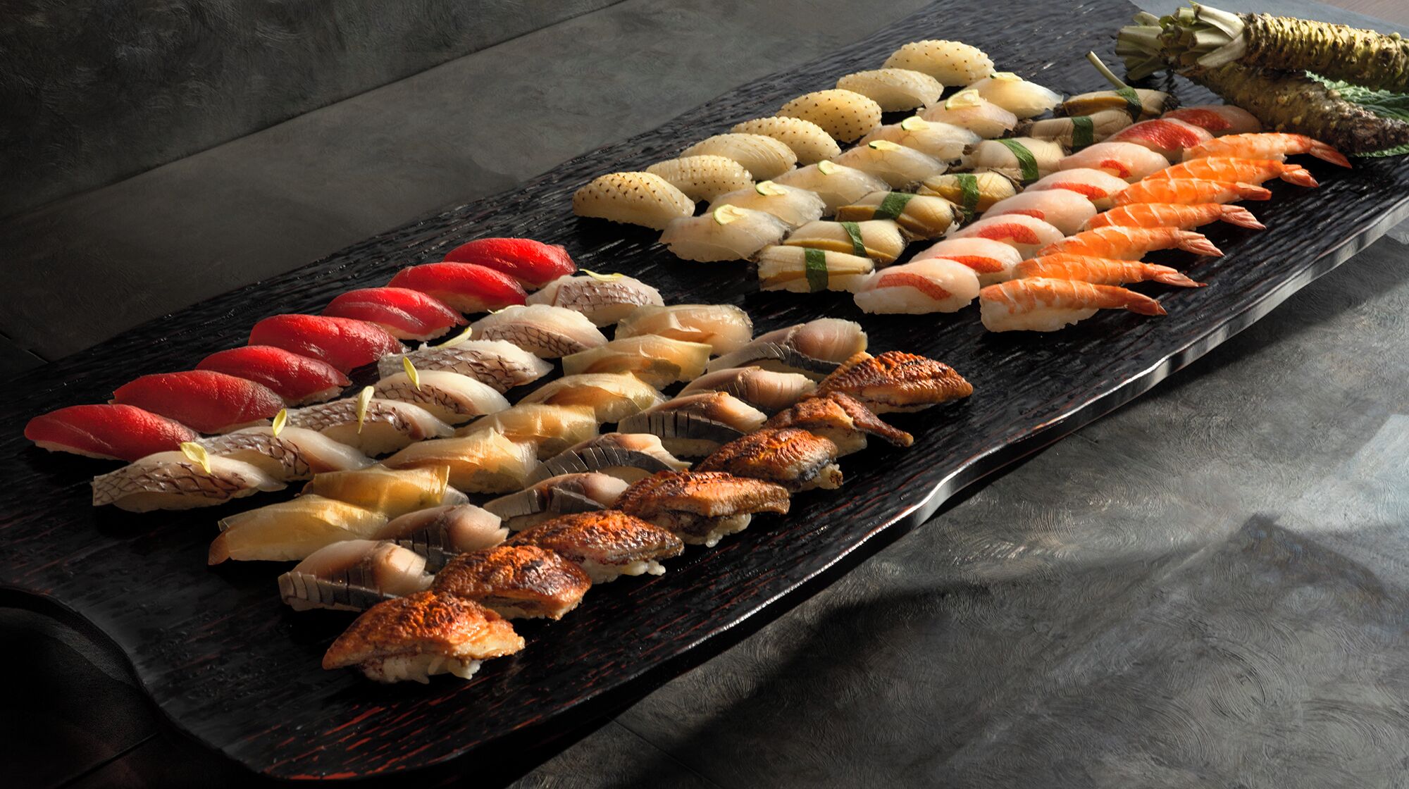 Variedad de sushi dispuesto sobre una tabla de pizarra negra.
