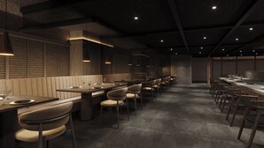 Un restaurant moderne doté de longues tables communes et de banquettes, avec un design minimaliste et un éclairage chaleureux.