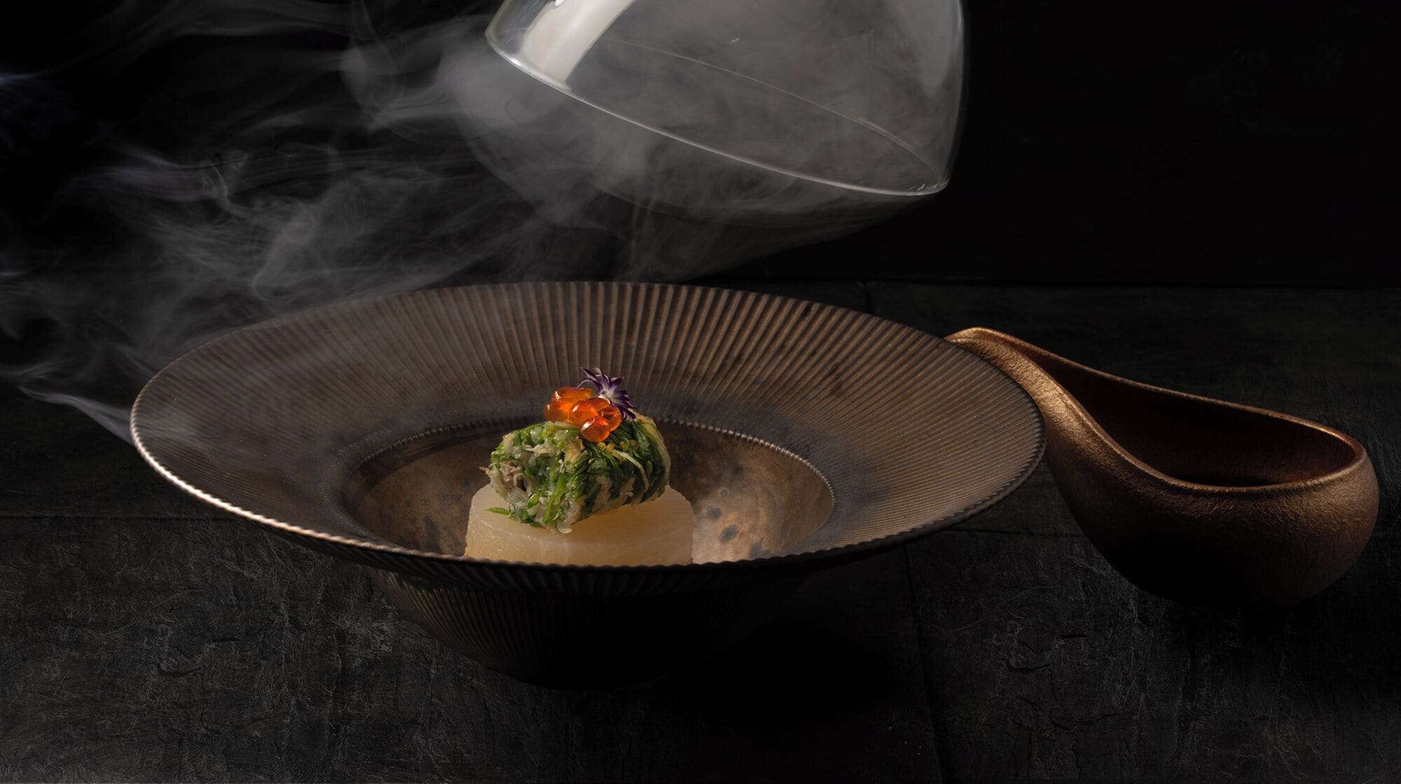 A bowl with a food item, a spoon, and smoke.