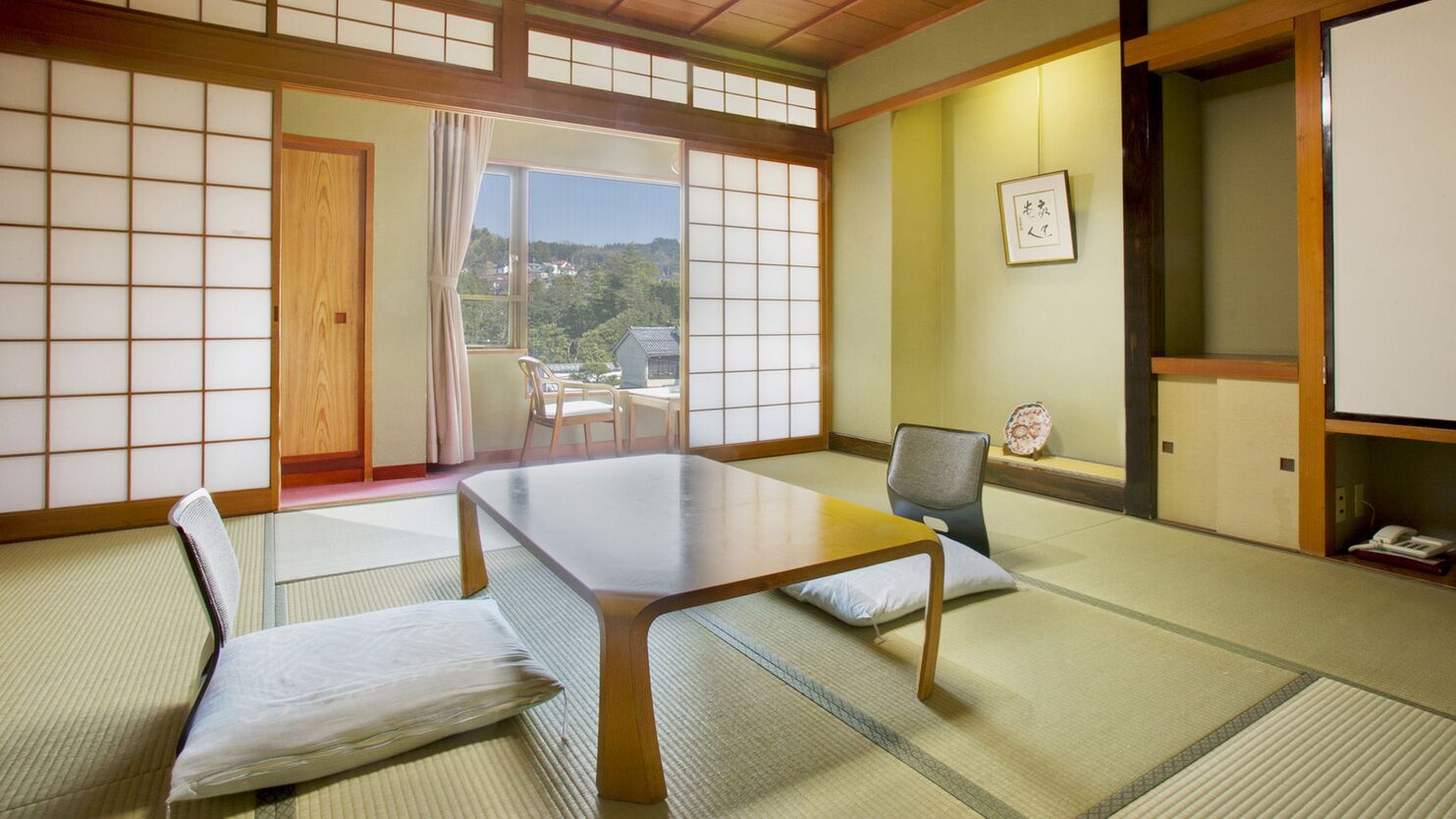 A traditional Japanese room with tatami flooring, a low table, and a sliding door leading to a balcony.