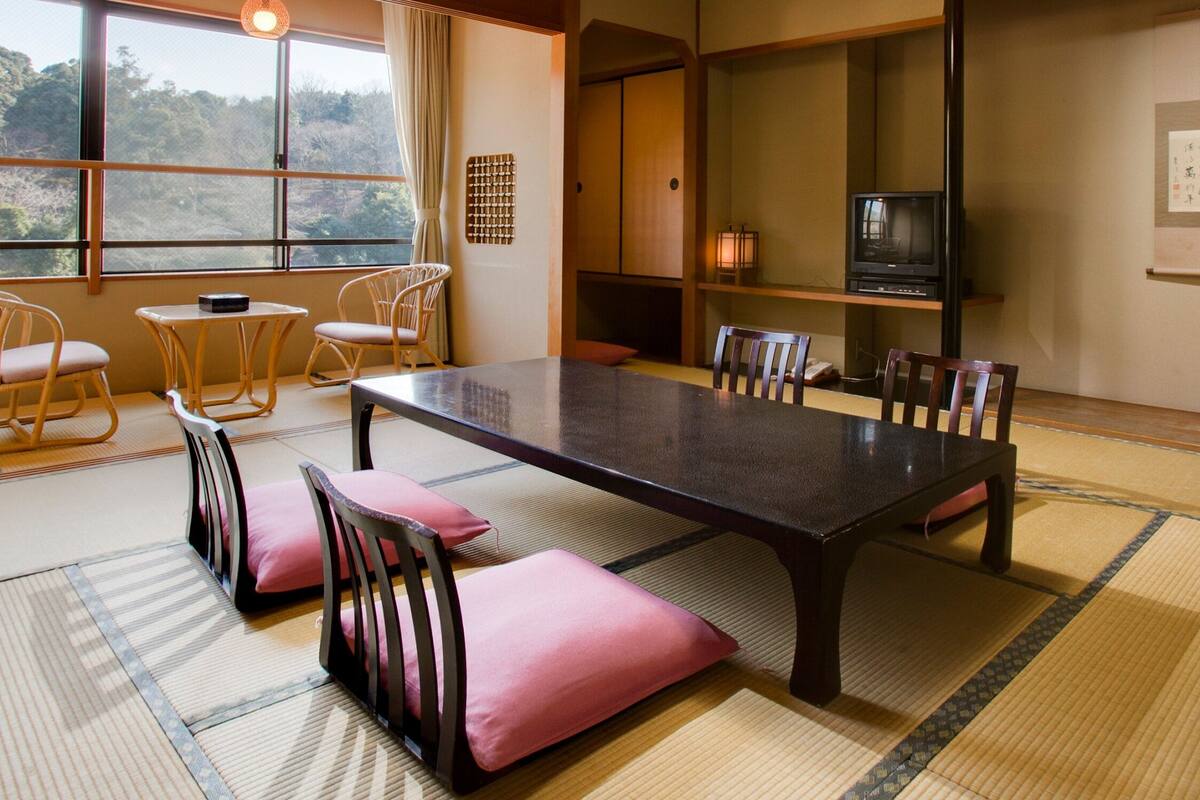 Une pièce de style japonais traditionnel, avec un sol recouvert de tatamis, une table basse et des chaises en bois.
