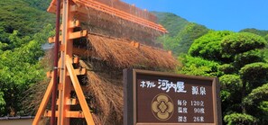 A traditional Japanese water wheel with a signboard indicating water temperature and depth. - Hotel Kawachiya (Minamiizu)