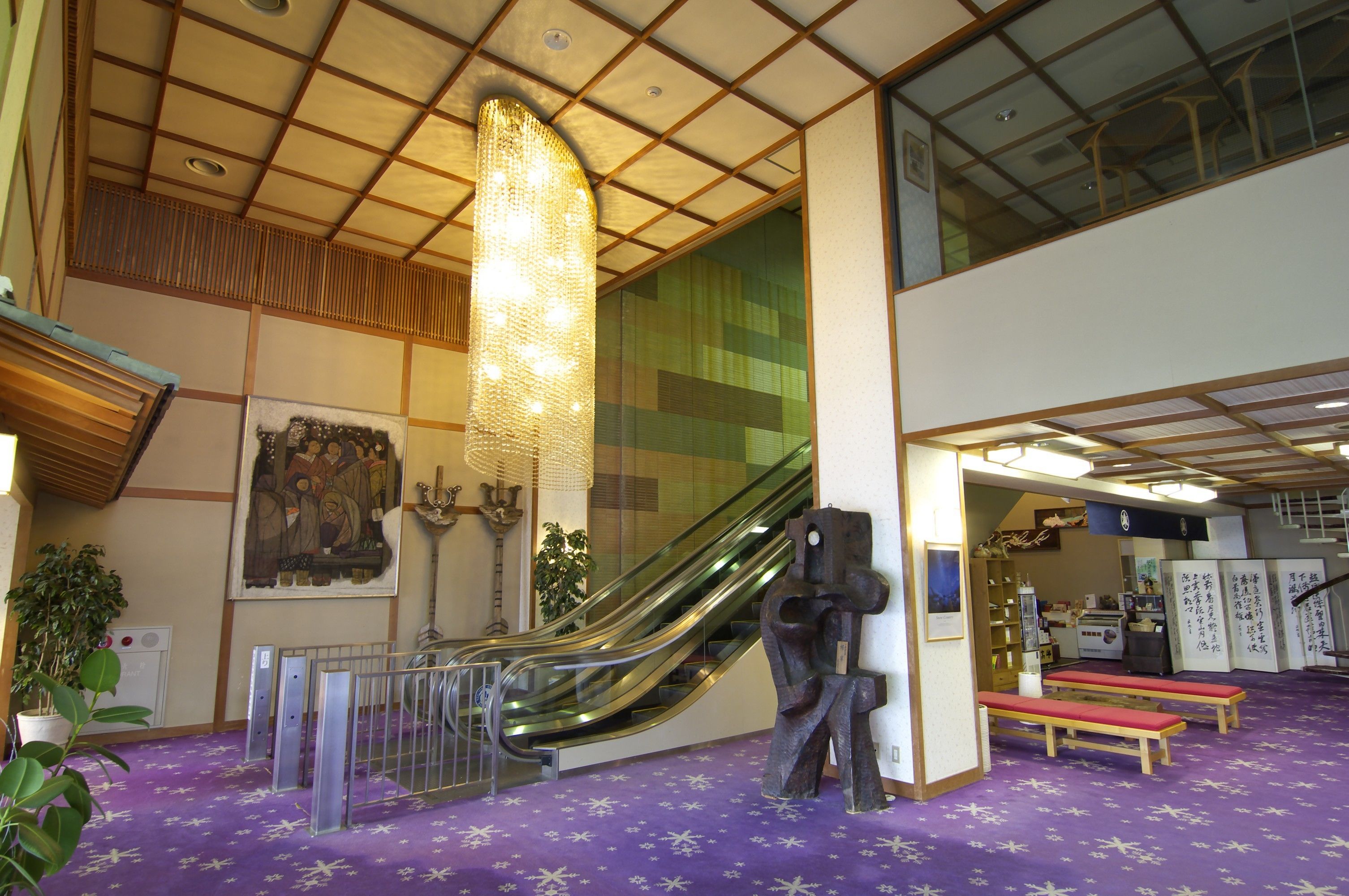 A lobby with a purple carpet, a staircase, and a large sculpture.