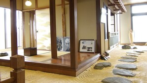 A traditional Japanese room with tatami flooring, a shoji screen door, and a wooden beam ceiling. - Takahan (Yuzawa)