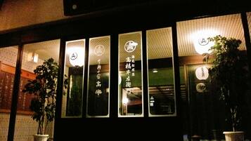 Fachada de edificio con varias ventanas, algunas con letreros iluminados.