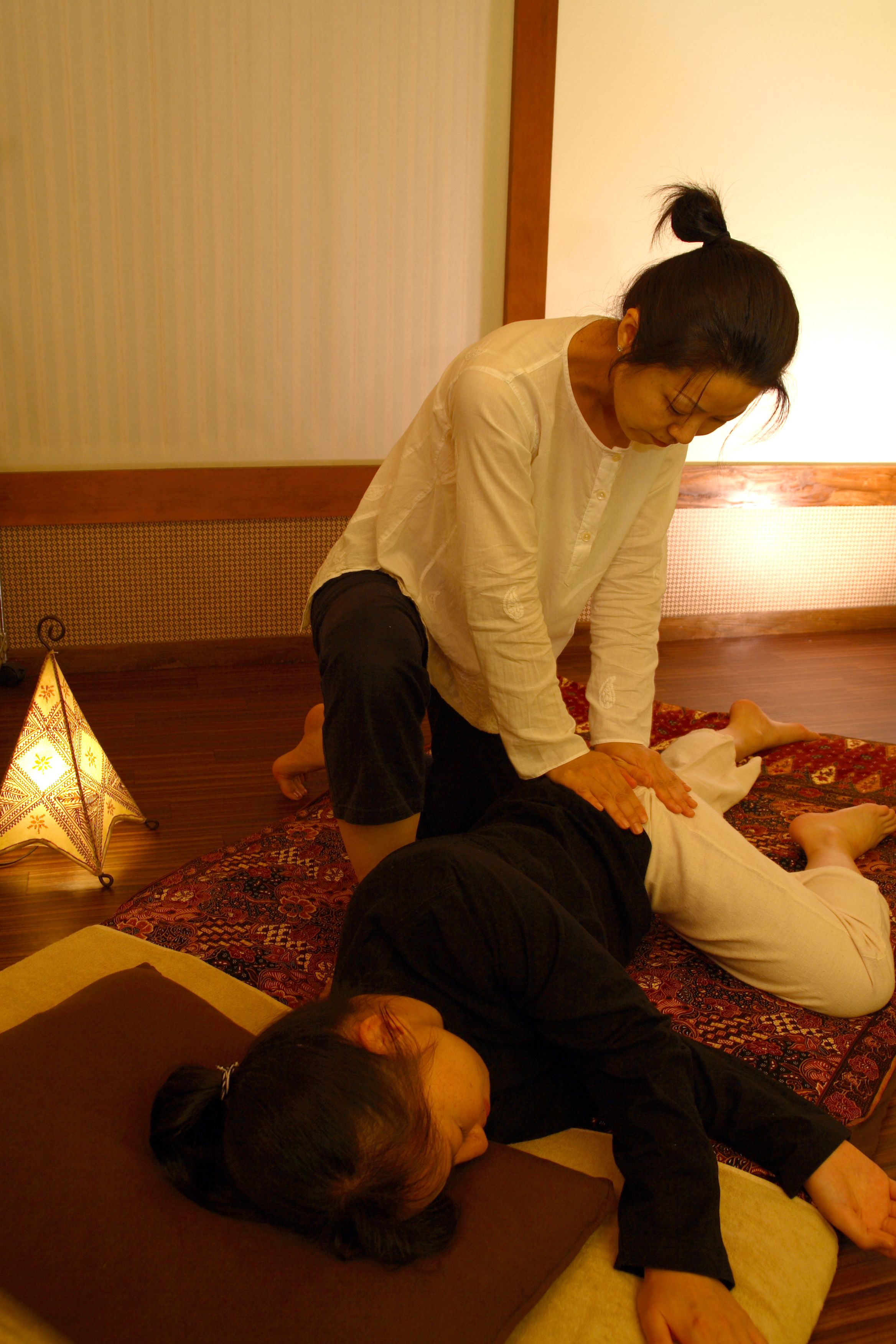 Une personne allongée sur un tapis et recevant un massage.