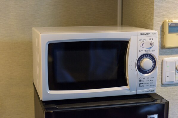 A microwave oven with a digital display and control panel, placed on top of a black appliance.