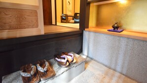 Perinteinen japanilainen huone, jossa on tatamimatto, matala pöytä teekupit ja -astiastot valmiina, sekä pieni alttari, jossa on kynttilä.