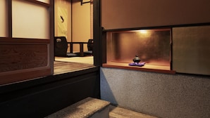 A traditional Japanese interior with tatami flooring, a low wooden table, and a shelf with a small incense burner. - Rinn Shijo Takasegawa (Kyoto)