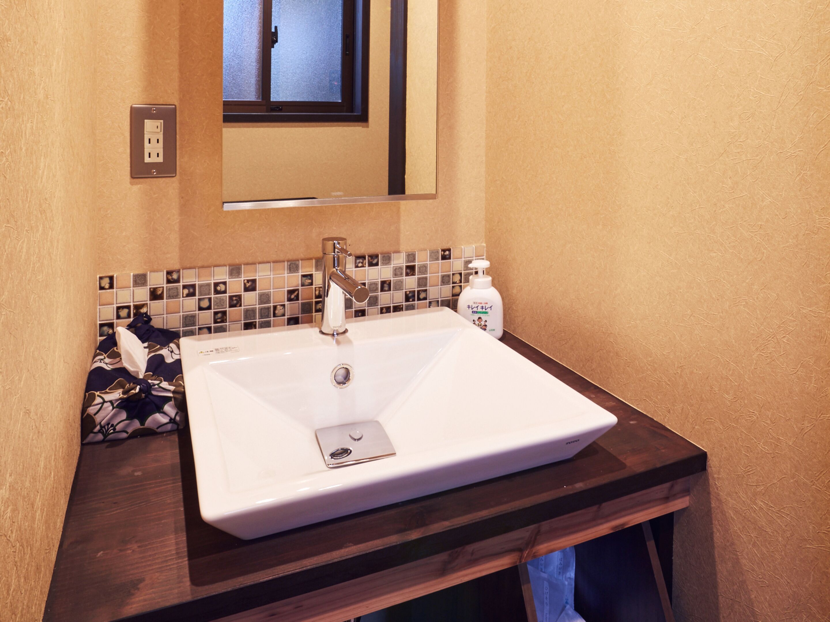 A bathroom with a white sink, a mirror above it, and a tiled backsplash.