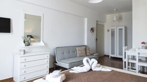Una stanza moderna e luminosa con un divano grigio, una cassettiera bianca e un'area pranzo.