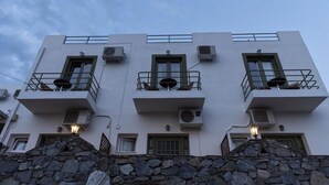 Un edificio a più piani con balconi, condizionatori e pareti in pietra.