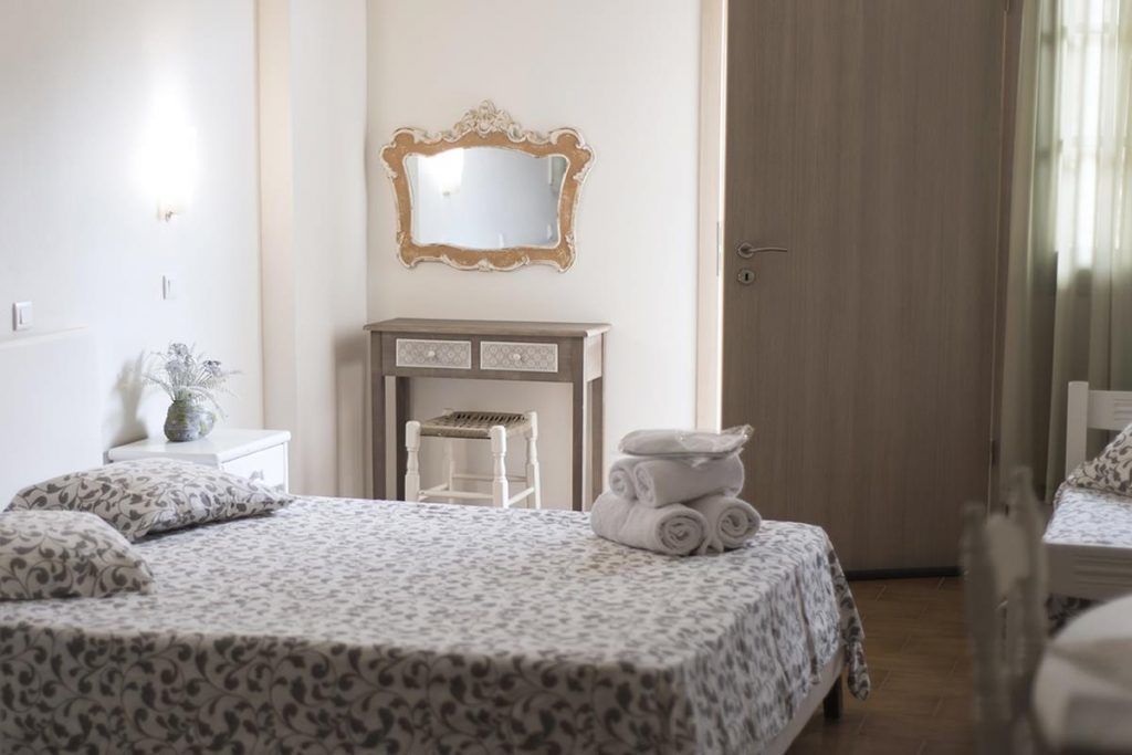 Un dormitorio con cama, cómoda, espejo y puerta.