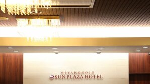 Een modern ontworpen receptiebalie bij Miyakonoto Sun Plaza Hotel, met een kroonluchter erboven.