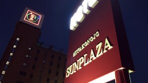 Een gebouw met een bord waarop 'SUNPLAZA' staat en een logo met een groene cirkel en een rode figuur.