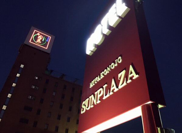 A building with a sign that reads "SUNPLAZA" and a logo with a green circle and a red figure. - Sun Plaza Hotel (Miyakonojo)