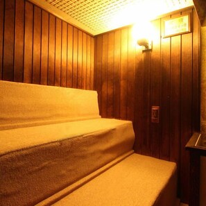 A wooden room with a bench and a wall-mounted light fixture. - Sun Plaza Hotel (Miyakonojo)