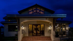Una casa moderna con un amplio acceso de vidrio, un porche cubierto y un interior bien iluminado.
