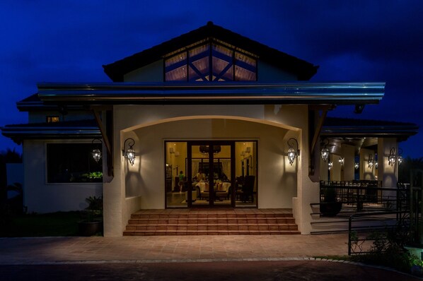 A modern house with a large glass entrance, a covered patio, and a well-lit interior. - Espacio Verde Resort (Roxas City)