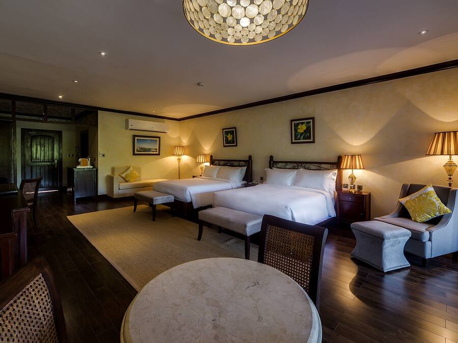 Ein Hotelzimmer mit einem großen Bett, zwei Nachttischen, einem runden Tisch und einem Stuhl.