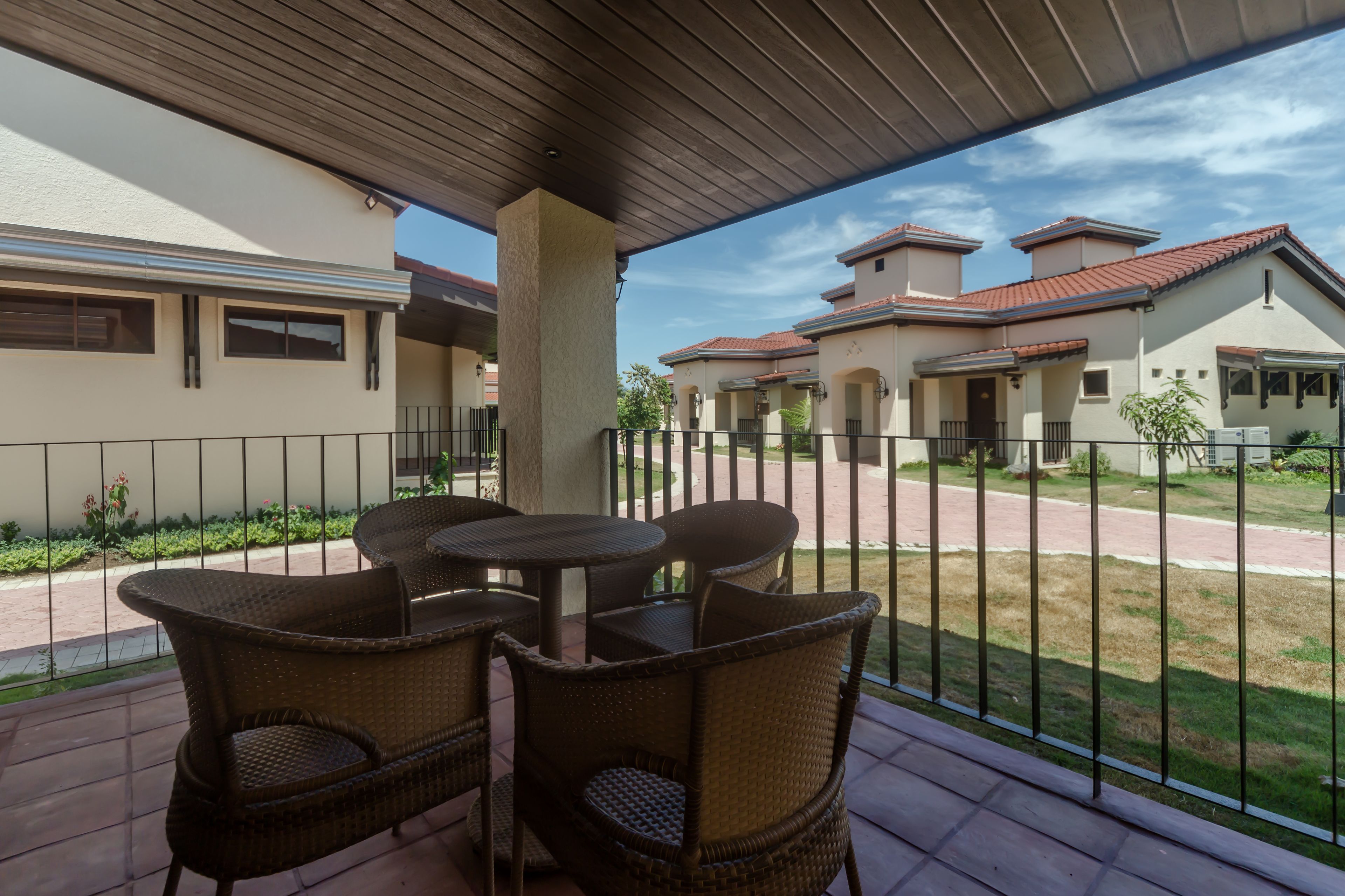 A covered patio area with wicker furniture and a view of neighboring houses.