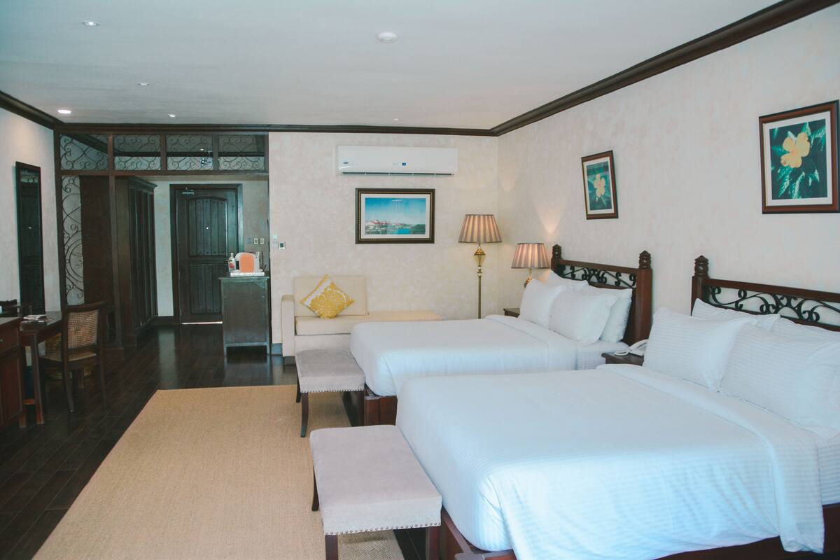 Una habitación de hotel con dos camas, un sofá, un escritorio y una silla.
