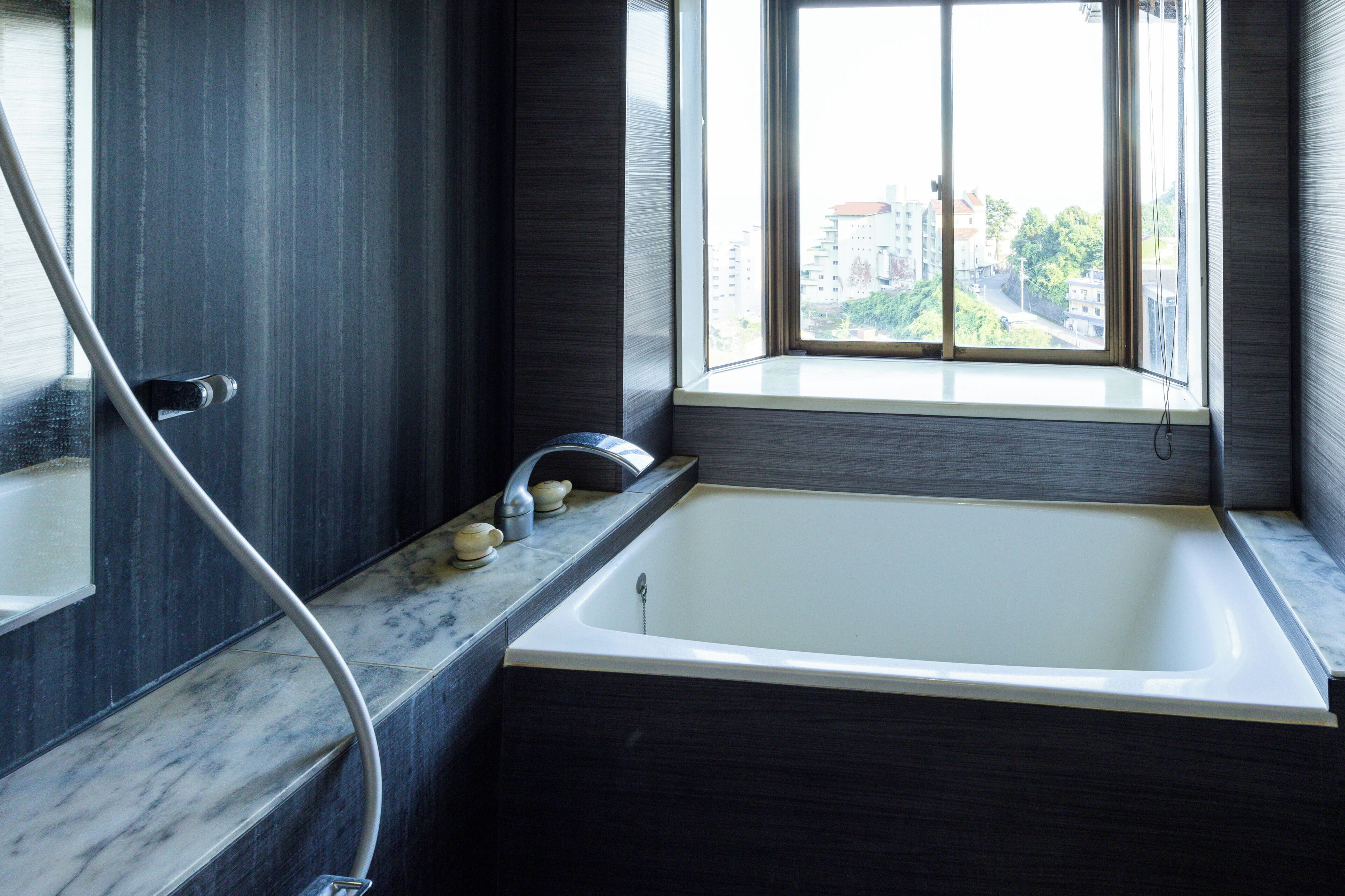 Un baño moderno con bañera, ventana y encimera de mármol.