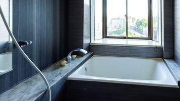 Un baño moderno con bañera, ventana y encimera de mármol.