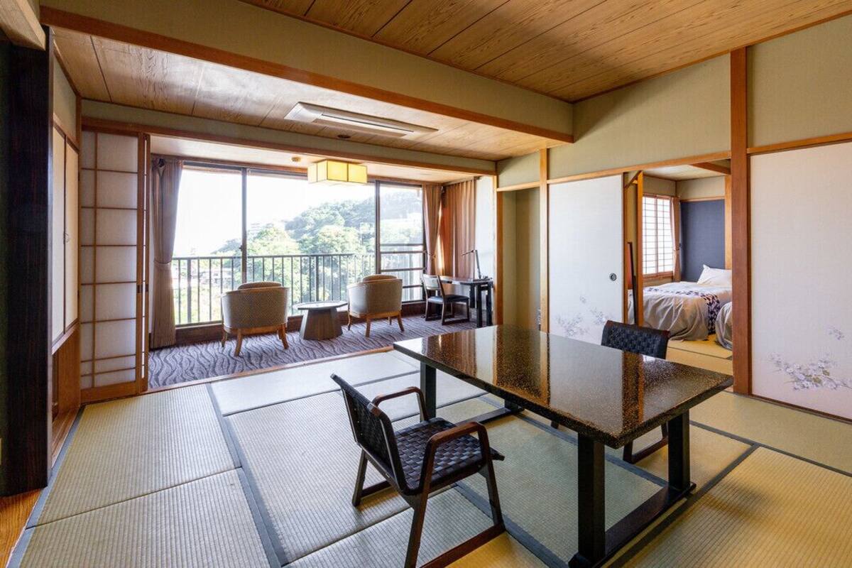 A traditional Japanese room with tatami flooring, a low table, and a bed with a shoji screen.