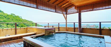 Una terraza de madera con un jacuzzi y vista al mar.