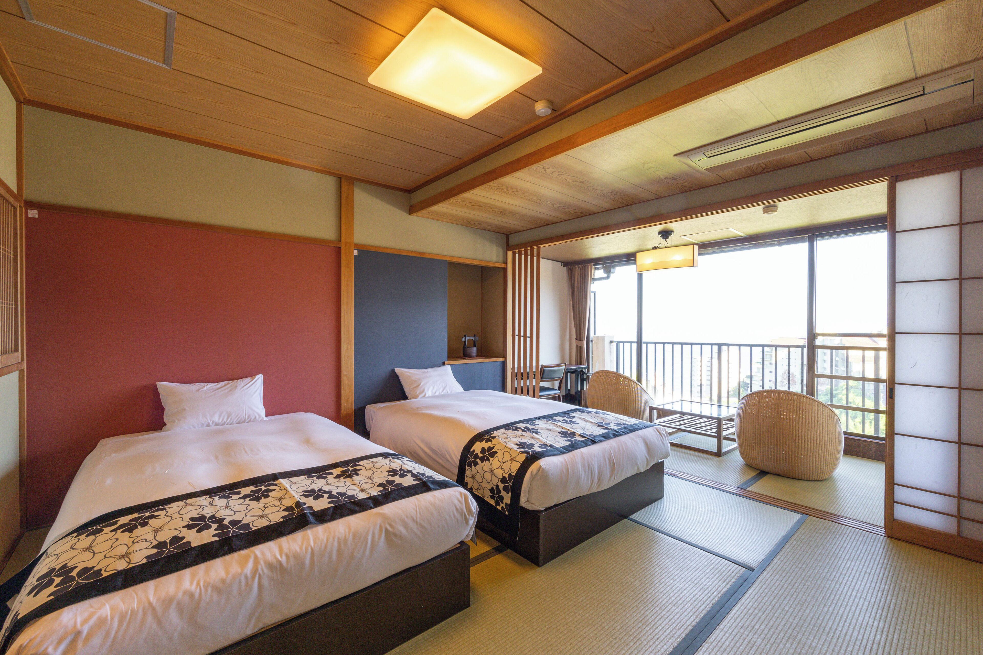 Ein Hotelzimmer mit zwei Betten, einem Balkon, Tatami-Böden und Blick ins Freie.
