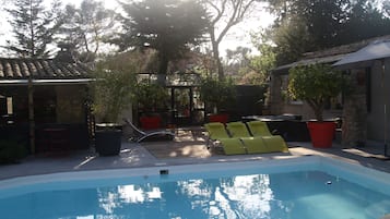 A swimming pool with lounge chairs and potted plants.