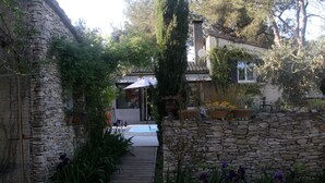 A stone pathway leading to a house with a wooden deck and a covered area. - Inn4bears (Nîmes)