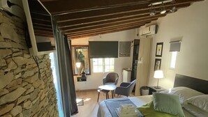 A bedroom with a stone wall, a bed with pillows, a black rug, and a wooden ceiling. - Inn4bears (Nîmes)