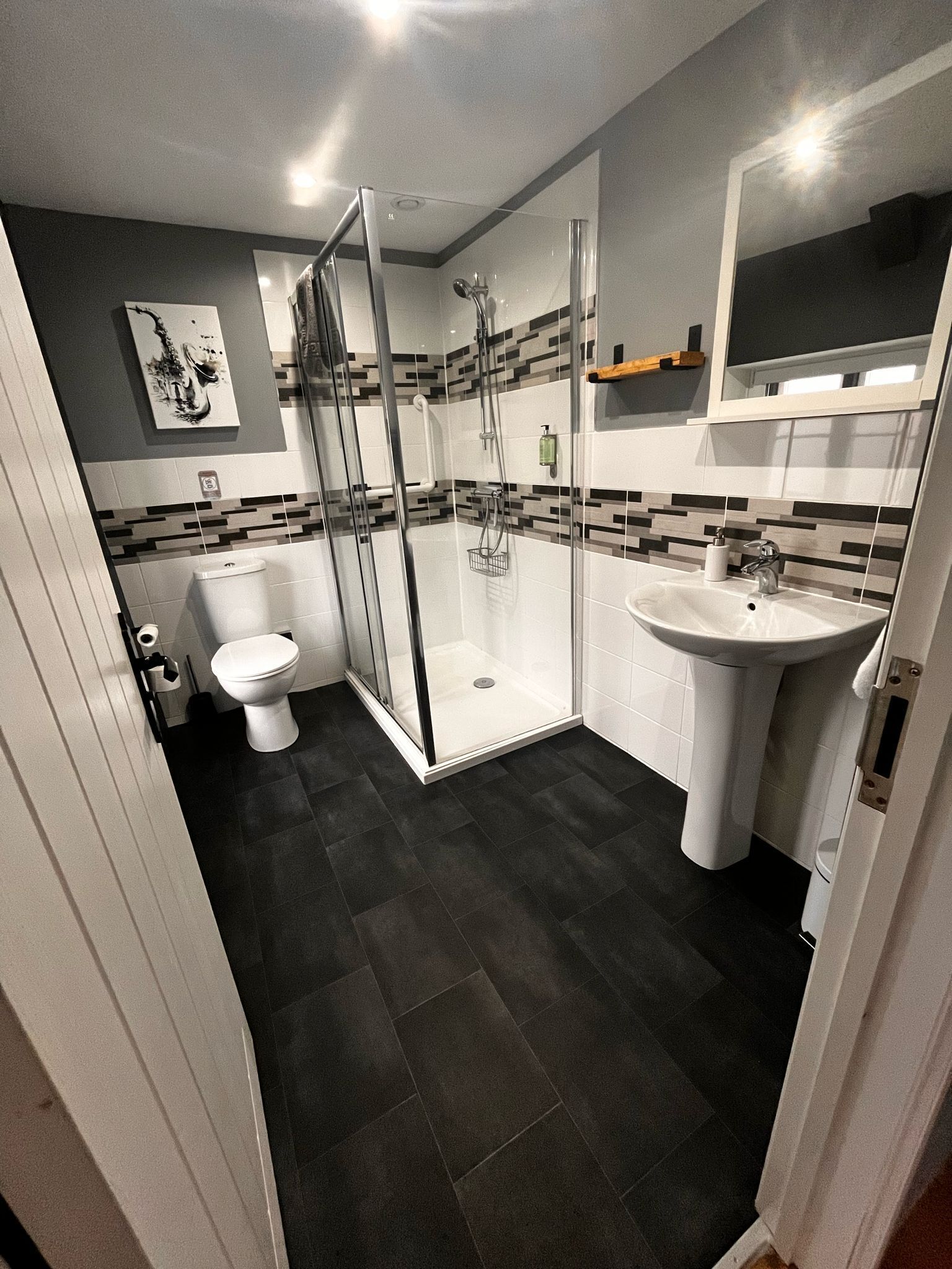 A modern bathroom with a glass-enclosed shower, a white sink, and a toilet.