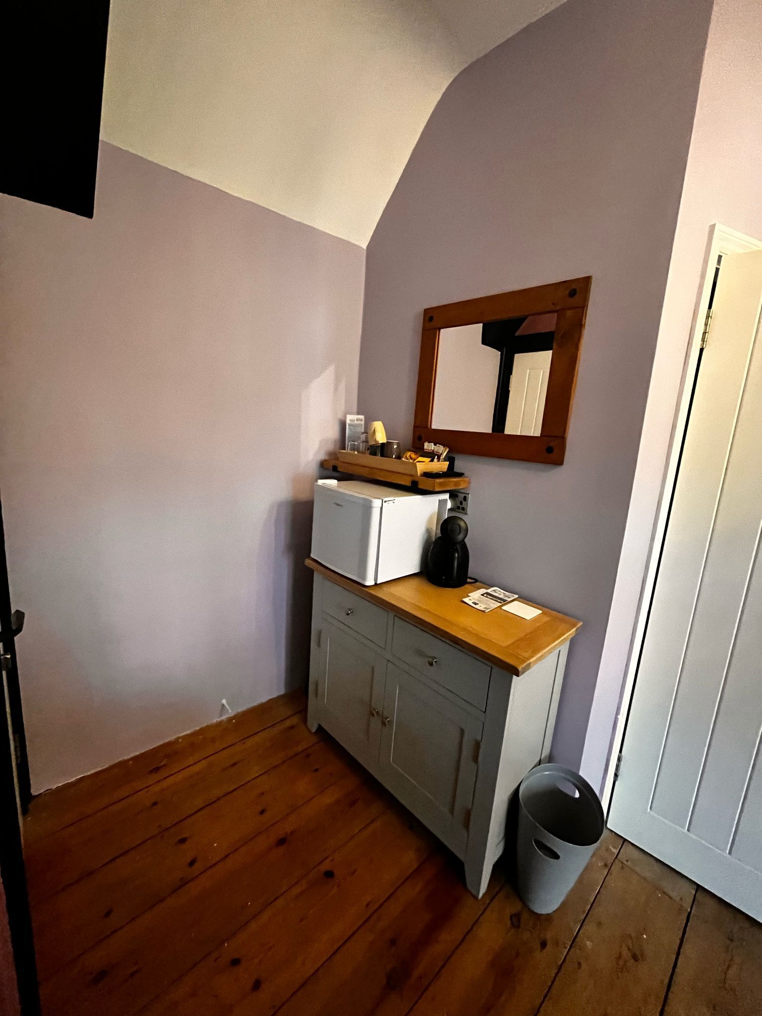 A small kitchenette with a refrigerator, a coffee maker, and a wooden countertop.