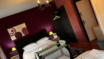 Un dormitorio con cama, mesita de noche, lámpara, candelabro, puerta y pared con diseño geométrico.