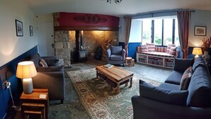 A cozy living room with a stone fireplace, a sofa, a coffee table, and a bookshelf.