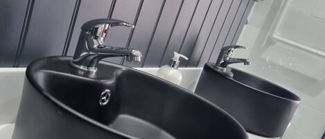 A bathroom with two black sinks, a mirror, and a tiled floor.