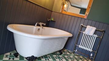 A bathroom with a freestanding bathtub, a mirror, and a radiator.