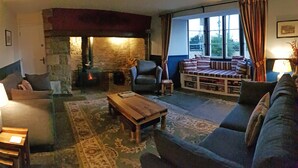 A cozy living room with a stone fireplace, a sofa, a chair, and a coffee table.