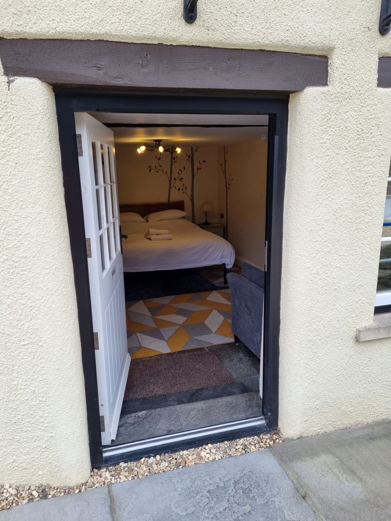 Un dormitorio con cama, mesita de noche y lámpara de pared.