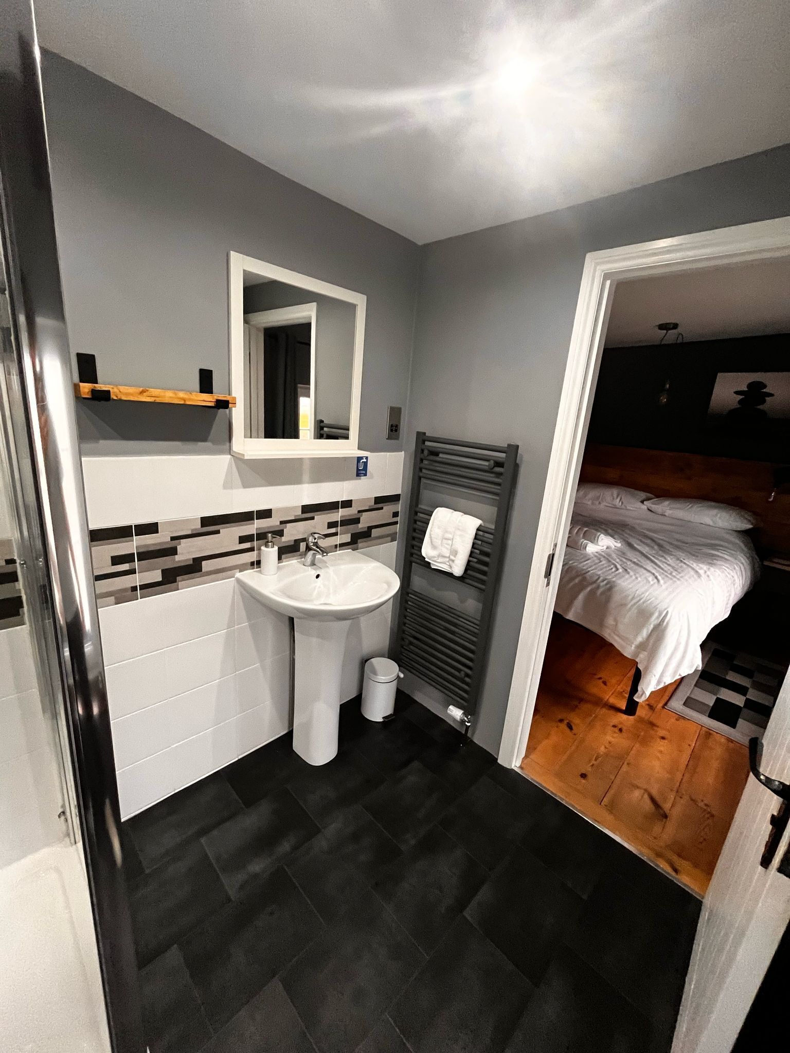 A compact bathroom with a white sink, mirror, and towel rack.
