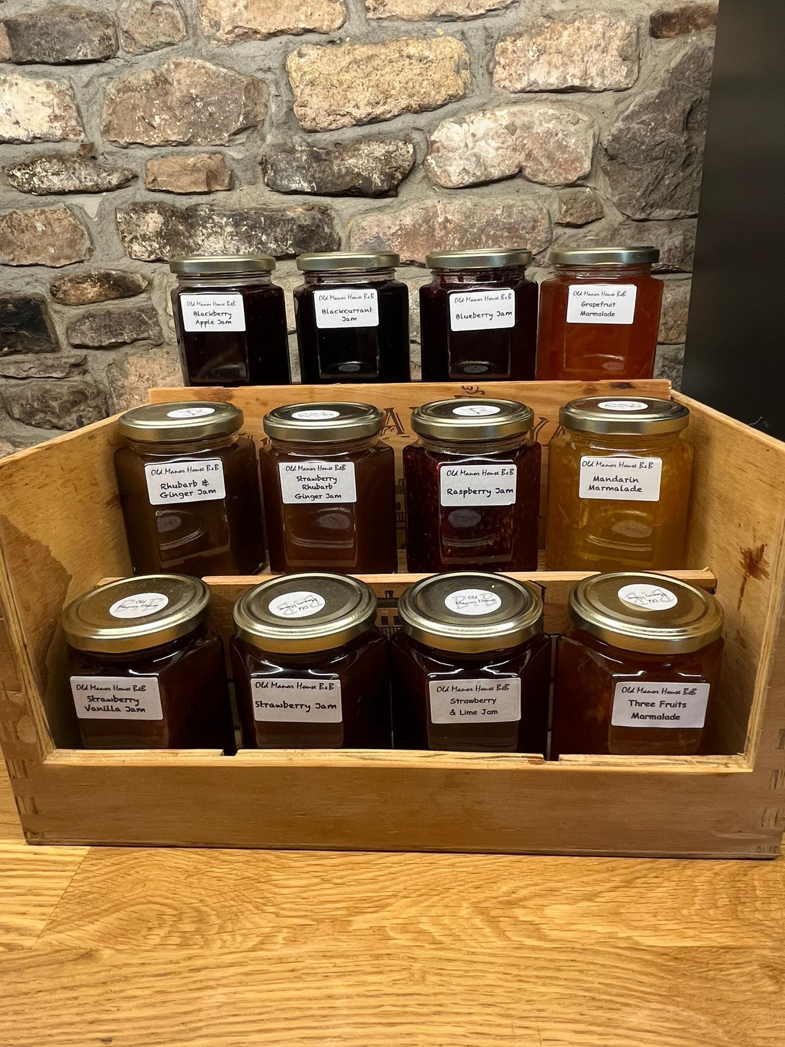 Une vitrine en bois contenant divers pots de confitures et de marmelades faites maison.