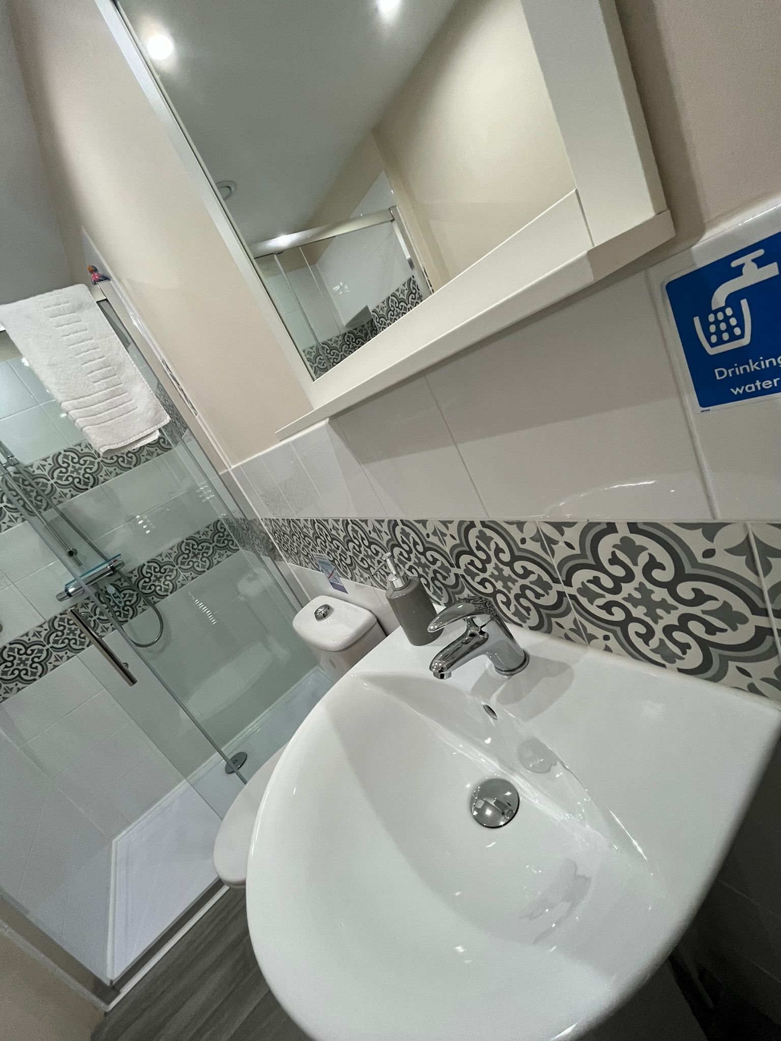Un bagno con un lavandino bianco, una cabina doccia in vetro e un water.