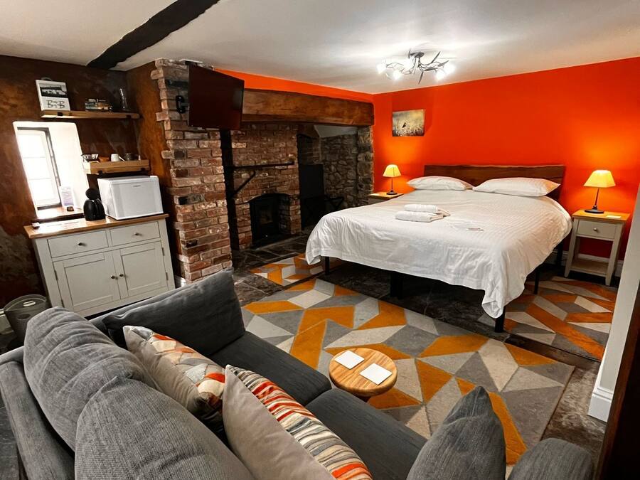 A bedroom with a bed, a sofa, a fireplace, and a nightstand with lamps.