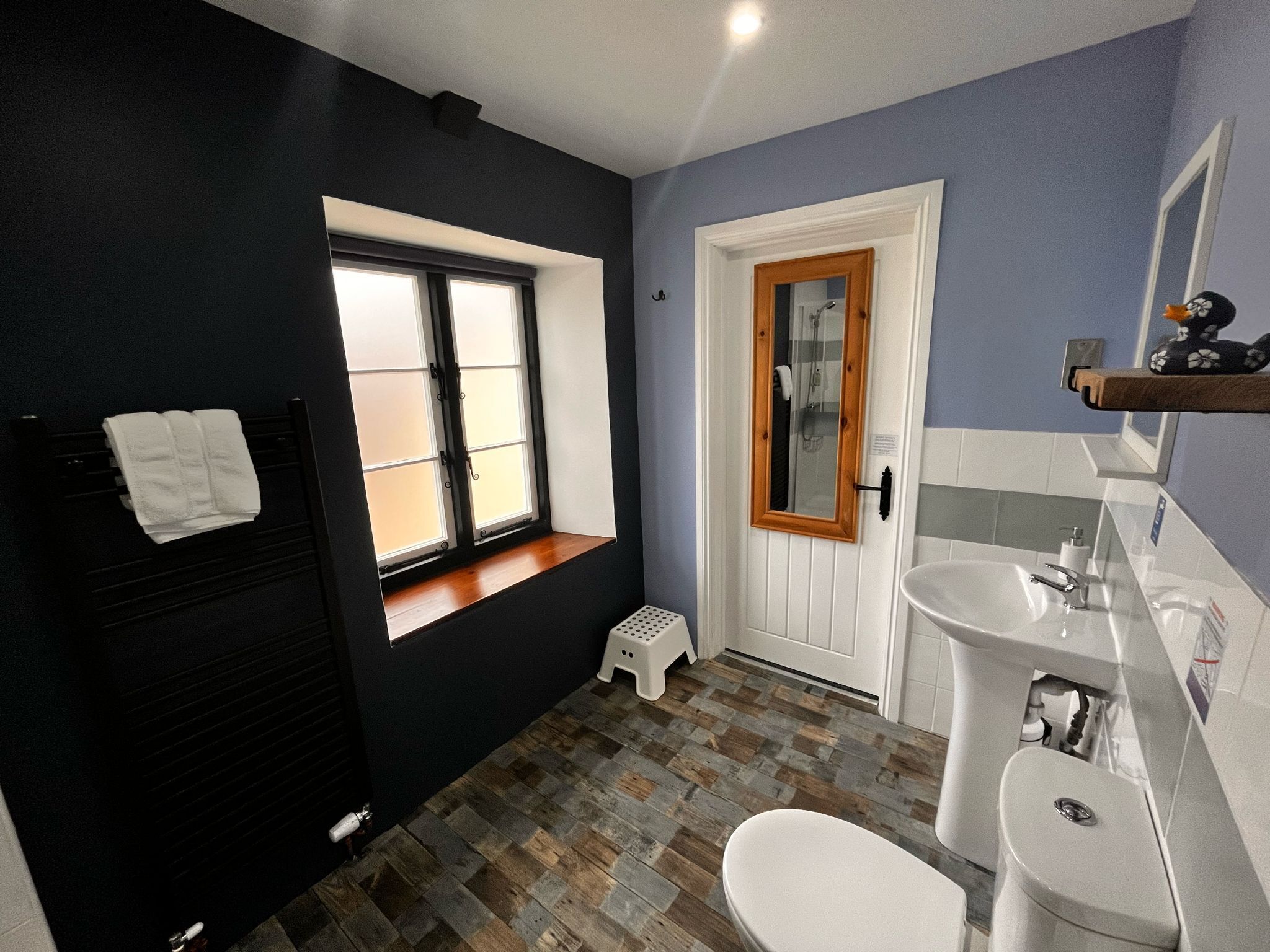 Un baño con ventana, un lavamanos blanco y un inodoro blanco.