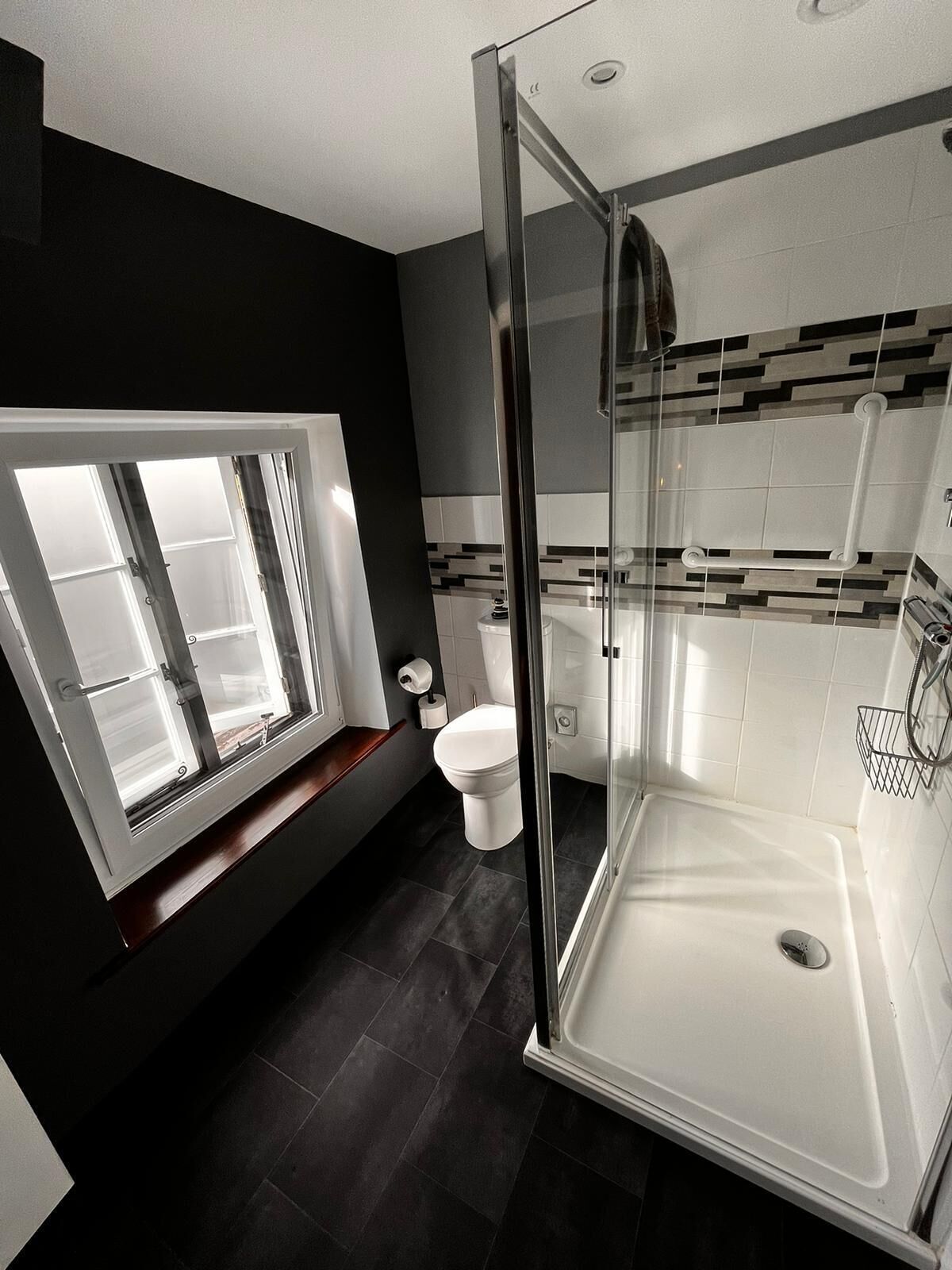 Un baño moderno con ducha de vidrio, inodoro y ventana con vidrio esmerilado.