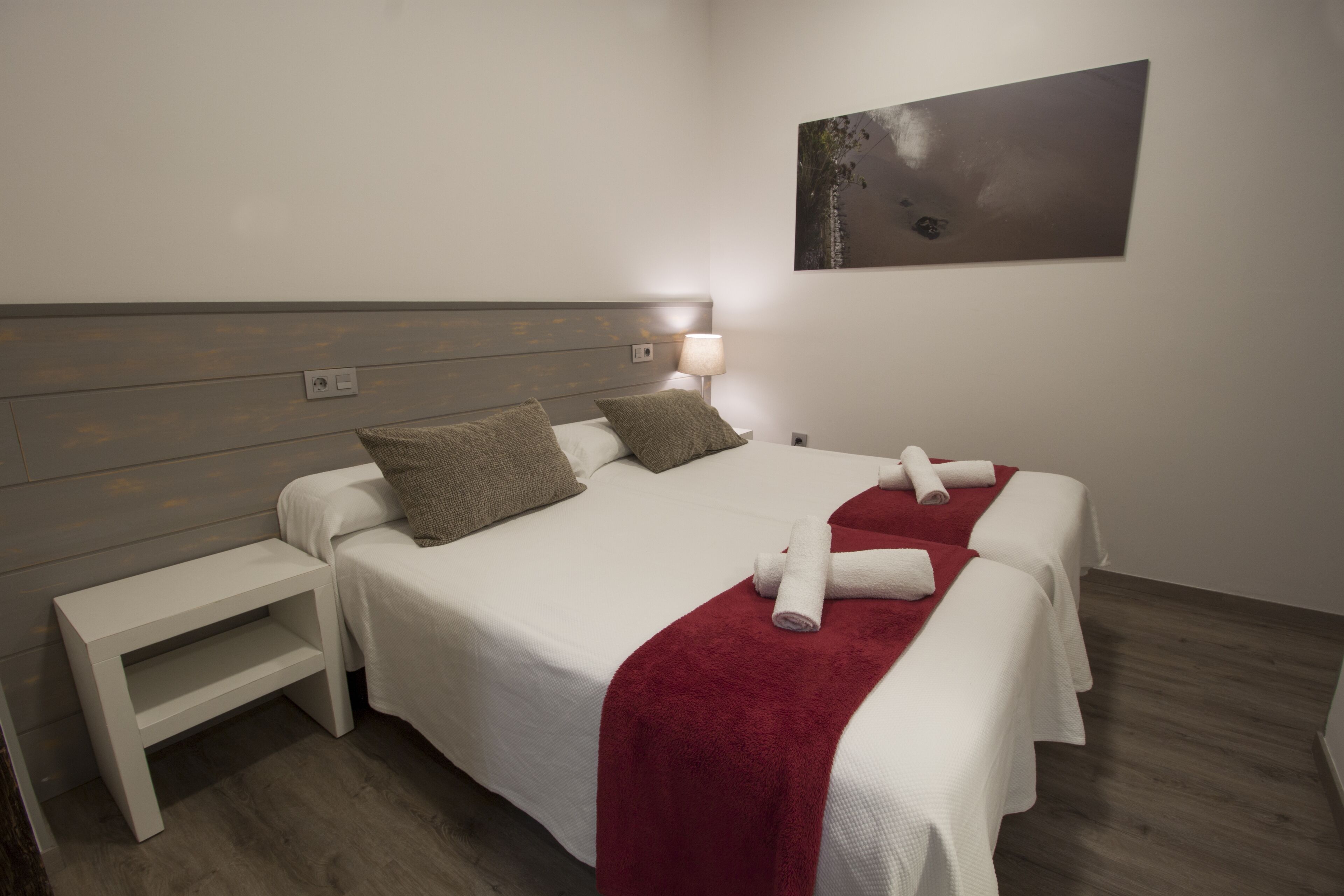 A hotel room with a bed, a nightstand, and a painting on the wall.